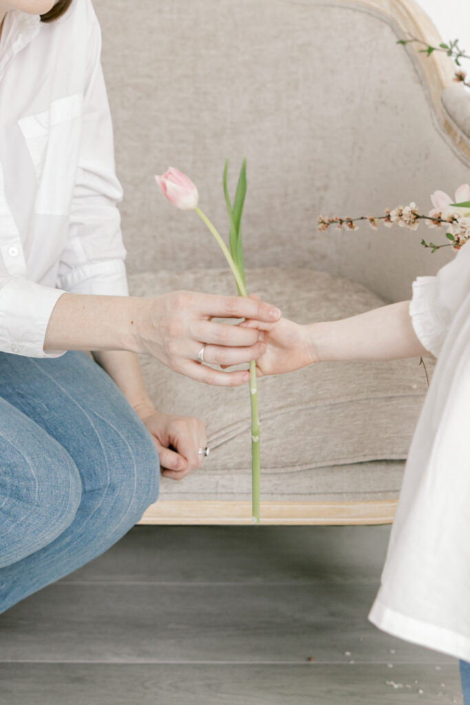 Close-up of mother and child holding hands with a flower during a Northern Virginia motherhood session