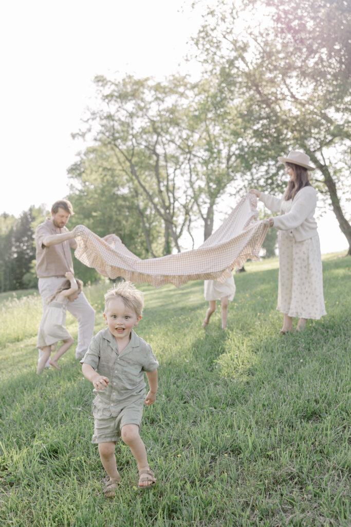Family holding blanket in the air while their son runs through