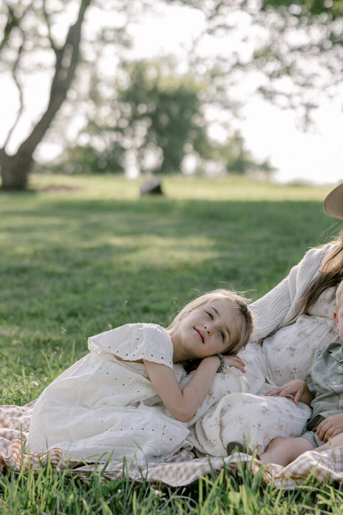Girl resting on her mothers leg on a picnic blanket