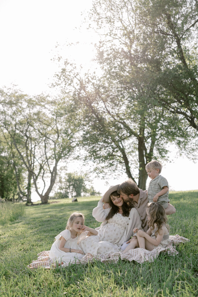 Family sitting on a picnic blanket during a relaxed summer family photo session in the park