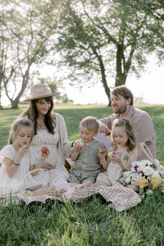 Family sitting on a picnic blanket during a relaxed summer family photo session in the park