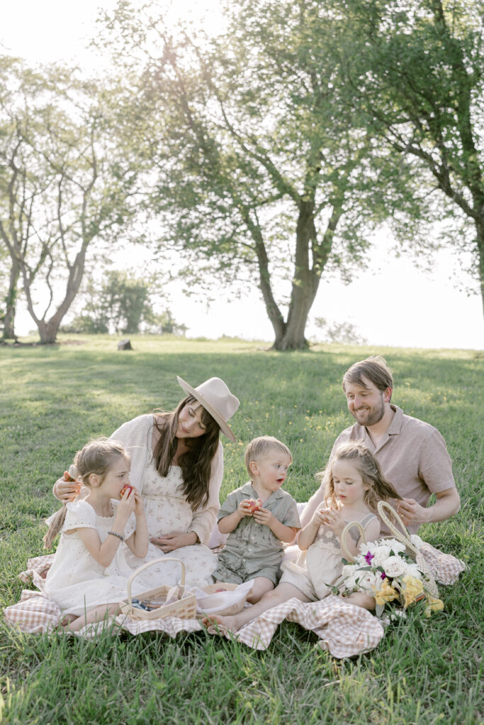 Family sitting on a picnic blanket during a relaxed summer family photo session in the park