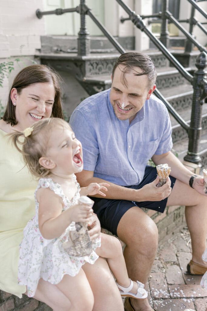 A family laughing together outside an Old Town Alexandria ice cream shop during a lifestyle photo session.