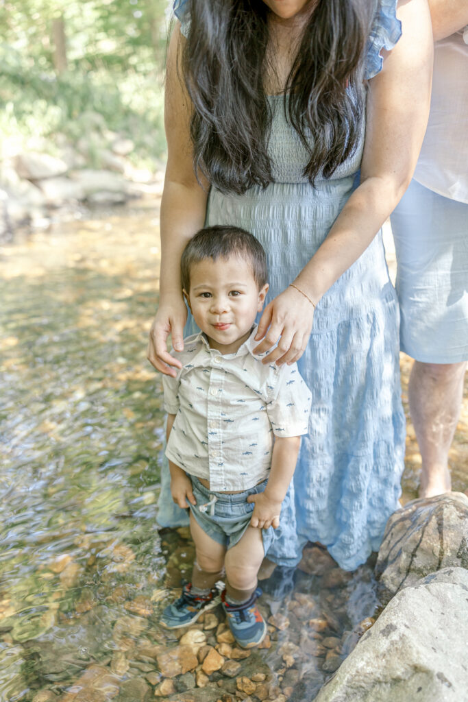 A family splashing and skipping rocks in a shallow creek, a top choice for summer family photo ideas in Northern Virginia.