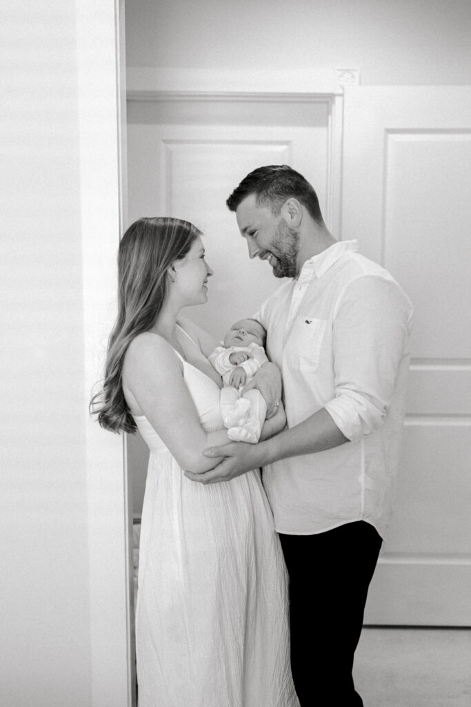Parents lovingly holding their newborn baby in a cozy Old Town Alexandria bedroom