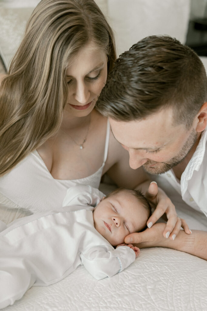 Parents lovingly holding their newborn baby in a cozy Old Town Alexandria bedroom