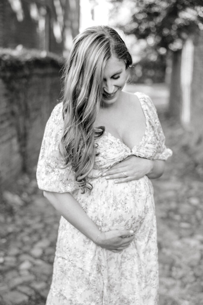 Pregnant woman holding her belly and smiling down in Alexandria VA