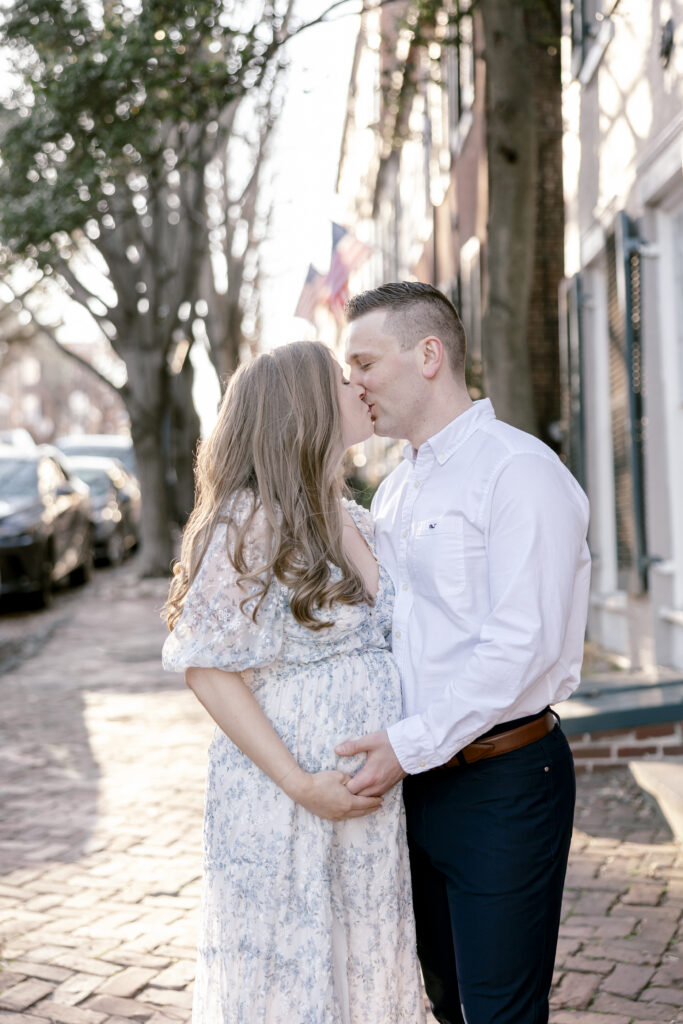 Couple kissing while holding a pregnant belly 