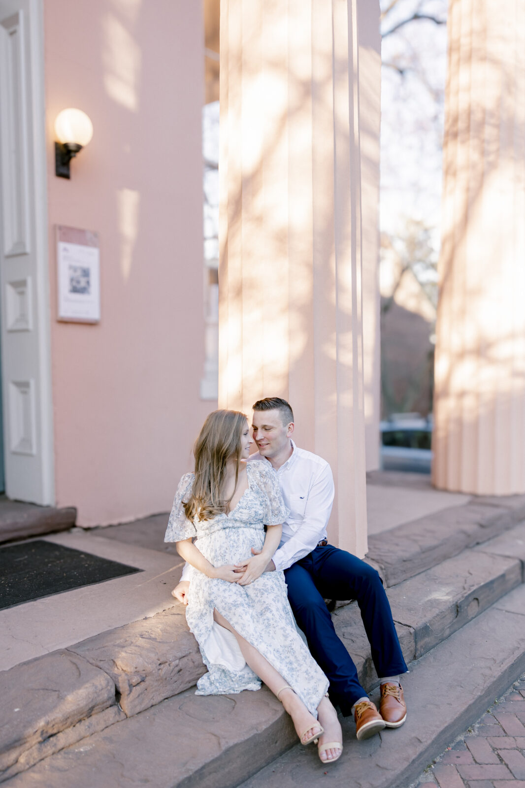 Husband and pregnant wife sitting on stairs looking at each other in Alexandria VA