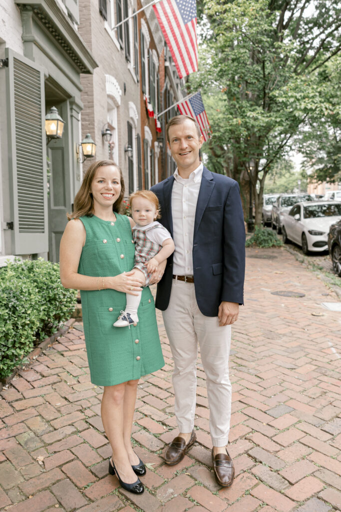 A woman and man holding their baby on a cobblestone street.