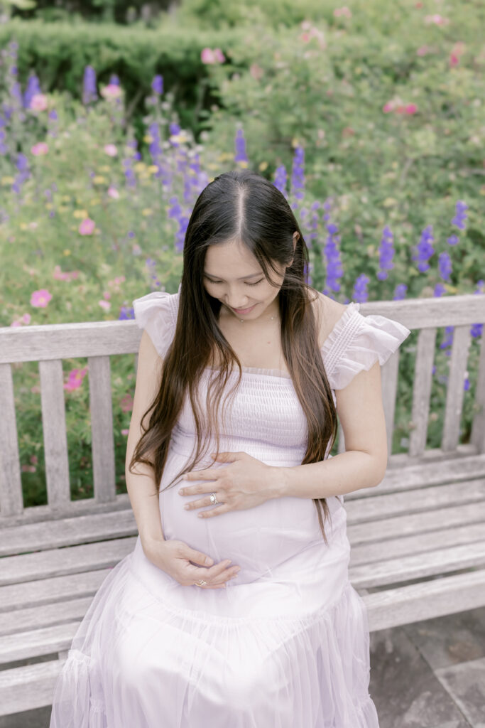 Pregnant woman sitting on a bench looking down at her belly in Washington DC