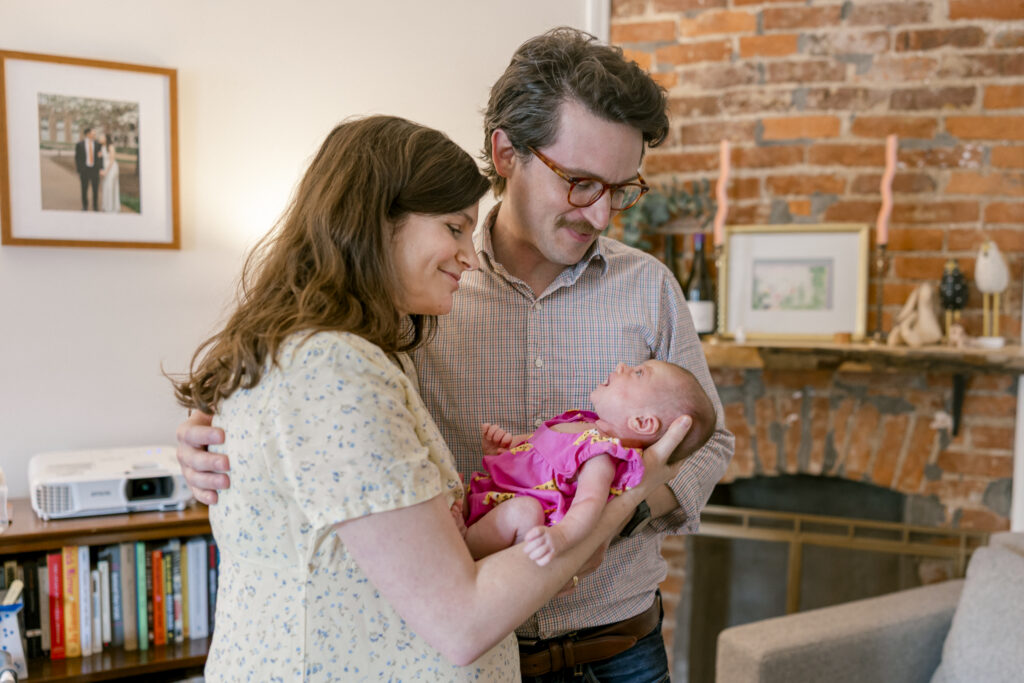 Newborn baby resting in parents arms during in-home newborn photography in DC