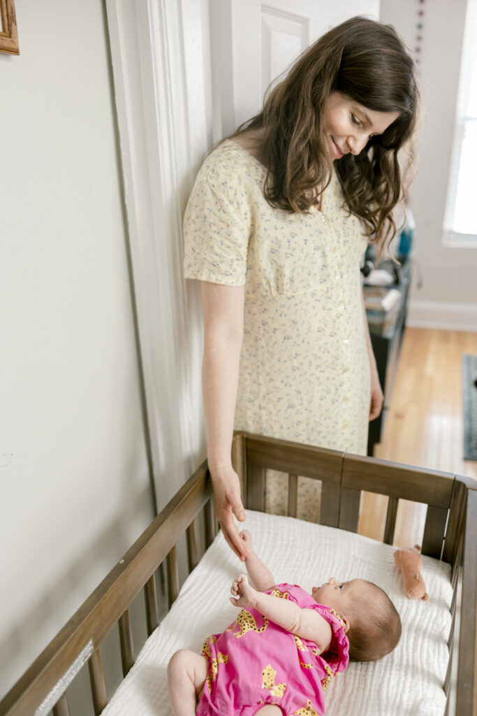 Mother standing by crib with newborn baby in Capitol Hill home during lifestyle newborn session