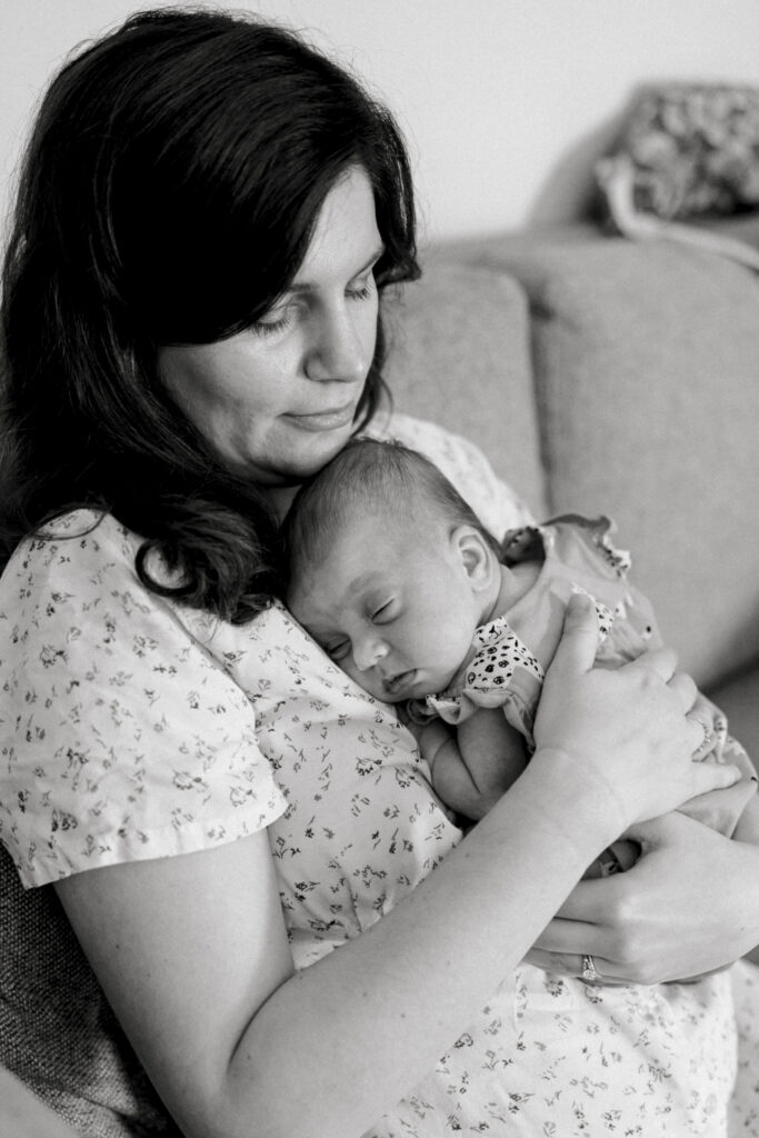 Mother holding newborn baby near window during DC in-home newborn photography