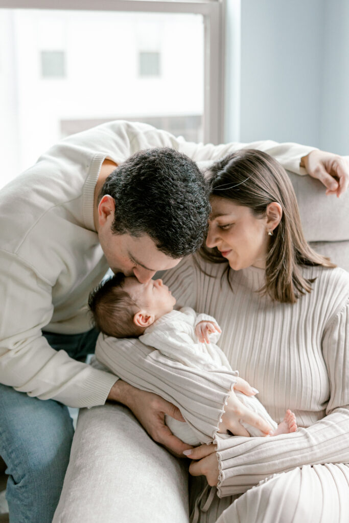 Candid family moment with newborn in softly lit bedroom