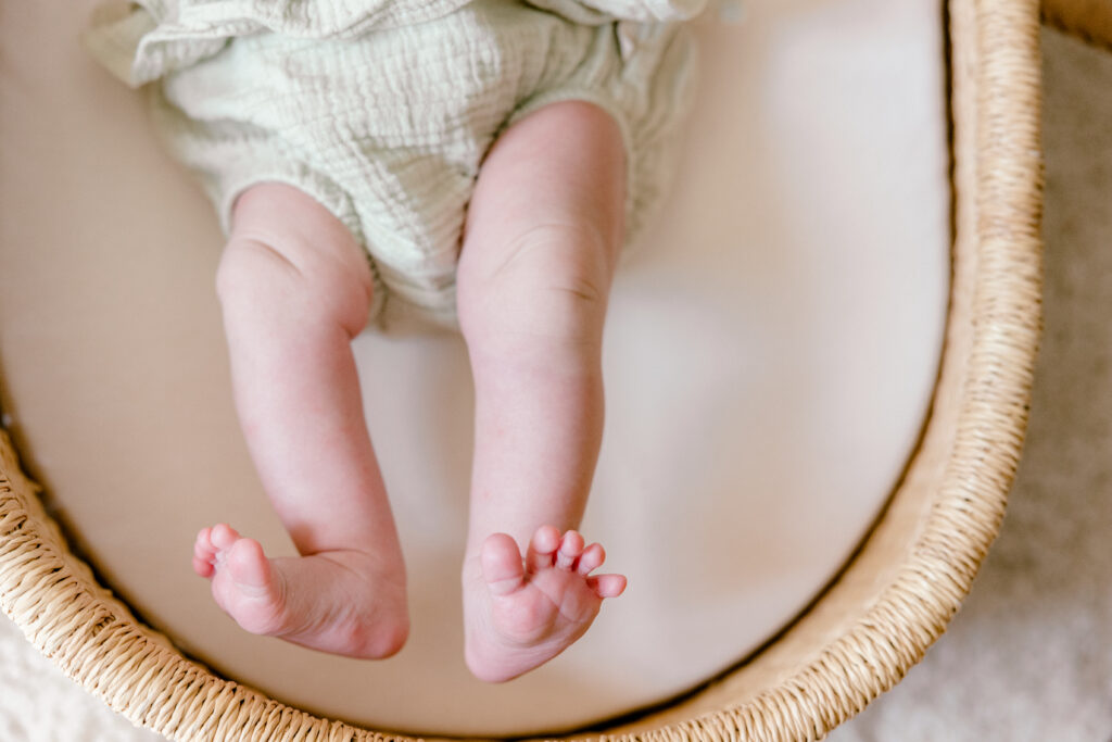 Close-up of a newborn baby’s feet in a calm in-home setting.