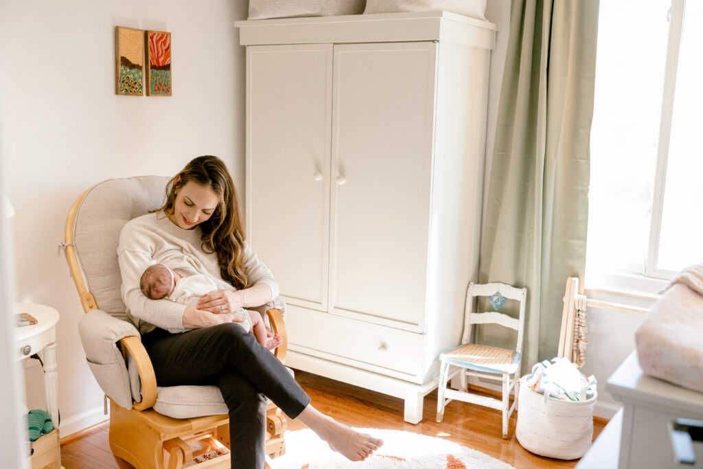 Mother looking down at her newborn while breastfeeding, capturing a quiet and tender postpartum moment.